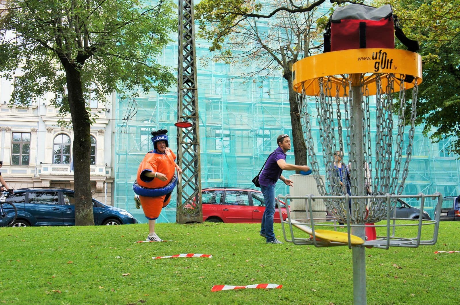 Rīgas centrā sumo tērpā cilvēks izmēģina disku golfu